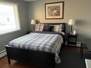 a bedroom with a bed with a plaid blanket and a window at Stardust Inn and Chalets in Pincher Creek