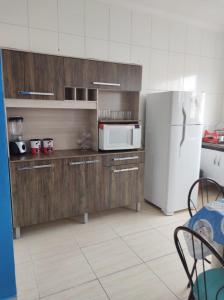 een keuken met een witte koelkast en houten kasten bij Casa na praia - Balneário Gaivotas in Itanhaém