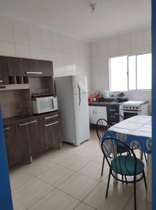een keuken met een tafel en een witte koelkast bij Casa na praia - Balneário Gaivotas in Itanhaém