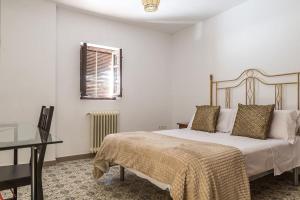 1 dormitorio con cama, mesa y ventana en Bienvenidos a la Casa del Realejo, en Granada