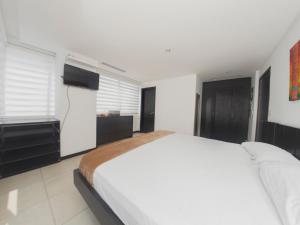 1 dormitorio blanco con 1 cama grande y TV en #2 Suite luxury - Puerto Santa Ana, en Guayaquil