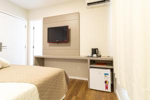 a bedroom with a bed and a tv on a wall at Gaivotas Praia Hotel in Florianópolis