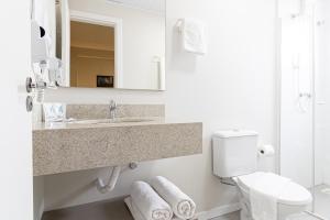 a bathroom with a sink and a toilet and a mirror at Gaivotas Praia Hotel in Florianópolis