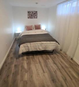 um quarto com uma cama grande e piso em madeira em Cozy 2-bedroom lower unit! em Barrie