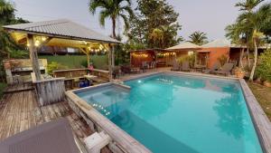 una gran piscina en un patio trasero con una casa en Baobab Guadeloupe, en Sainte-Anne