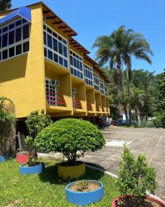 a yellow building with trees in front of it at Hotel Fazenda Bonanza in Engenheiro Paulo de Frontin