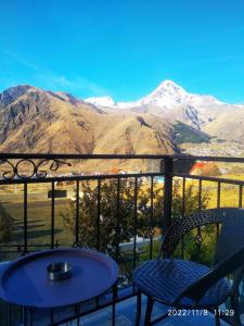 einen Tisch und zwei Stühle auf einem Balkon mit Bergblick in der Unterkunft UP in Kazbegi