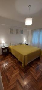 1 dormitorio con 1 cama amarilla grande y suelo de madera en Depto 3 amb con balcón Cochera Zona Casino Solo Familias en Mar del Plata