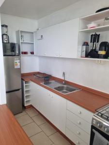 a kitchen with white cabinets and a stainless steel refrigerator at Departamento en Concepcion en Playa Bellavista Tome in Tomé