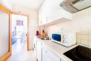 a white kitchen with a sink and a microwave at Apartamento La Salle in Seville