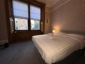 a bedroom with a white bed with a large window at Bright 3 Bedroom Edinburgh City Apt in Edinburgh