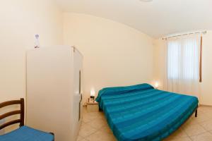 una camera con letto blu e frigorifero di Casa Vacanze Porto Corallo a Villaputzu