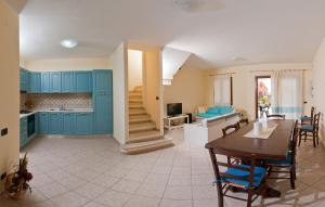 una cucina e una sala da pranzo con mobili blu e tavolo di Casa Vacanze Porto Corallo a Villaputzu