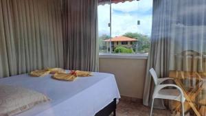 a bedroom with a bed and a large window at Suites Canoa in Aracati