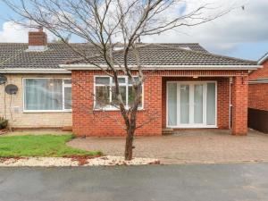 a brick house with a tree in front of it at Maple House in Tadcaster