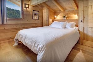sypialnia z łóżkiem w drewnianym domku w obiekcie Chalet Le Charmieux - OVO Network w mieście Le Grand-Bornand