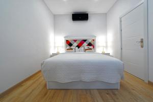 a white bedroom with a bed and two lamps at CASA VERDE Comfortable Air-Conditioned Modern Apartments in Ingenio