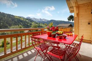 a red table with fruit and vegetables on a balcony at Chalet Le Charmieux - OVO Network in Le Grand-Bornand