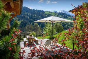 un patio con mesa, sombrilla y flores en Chalet Le Charmieux - OVO Network, en Le Grand-Bornand