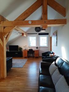 a living room with black leather furniture and wooden beams at Ferienhaus am Bach in Achslach