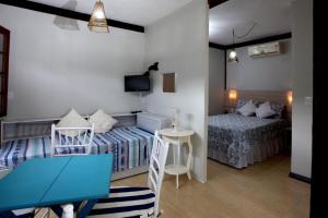 a room with two beds and a table and a desk at Recanto Vicks Flats in Ilhabela