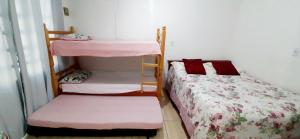 a bedroom with two bunk beds with pink sheets at KITNET S2 em TORRES-RS - Na mais bela praia Gaúcha - Cozinha - Banheiro - Ar condicionado - TV smart 32' - Wi-Fi - Estacionamento - Anfitriã Superhost no BnB in Torres +20 photos
