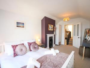 a bedroom with a white bed and a fireplace at Wolf Cottage in Weymouth