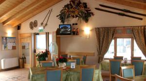 un restaurante con mesas y sillas y TV en la pared en Hotel La Colombina, en Livigno