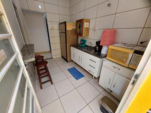 uma pequena cozinha com pisos e electrodomésticos em azulejos brancos em Quartos com Banheiros privativos - Hospedagem Recanto do Luar em Taubaté