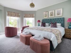 a bedroom with a large bed with two ottomans at Wansfell at Lipwood House in Windermere