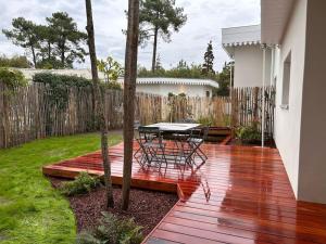 een patio met een tafel en stoelen op een houten terras bij Les Lodges de Saint Brice 1 in Arès