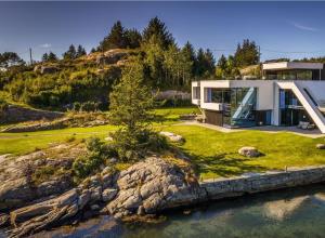 una grande casa su una collina con un corpo d'acqua di Unique villa by The Norwegian Coast. Private spa a Lokøy