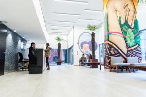 a lobby with palm trees and a mural at LivinnX Santiago in Santiago