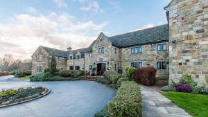 an exterior view of a large stone house with a driveway at Mercure Barnsley Tankersley Manor Hotel in Barnsley