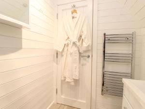 a white robe hanging on a door in a bathroom at The Shearer - Crossgate Luxury Glamping in Penrith