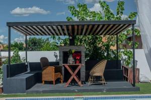 een pergola met stoelen en een tafel naast een zwembad bij Ellen Topo in Gaborone