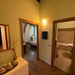 a bathroom with a mirror and a room with a bed at Guest-House Del Corso in Montepulciano