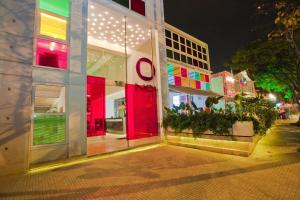 卡利Now Hotel Cali的街上的一座建筑,晚上有红色的门