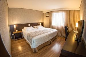 a hotel room with a bed and a window at Hotel Campo Largo Comfort in Campo Largo