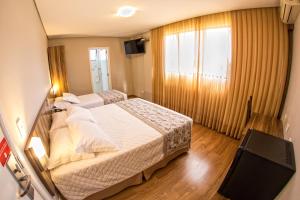 um quarto de hotel com duas camas e uma televisão em Hotel Campo Largo Comfort em Campo Largo