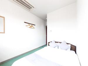 een slaapkamer met witte muren en een bed met witte kussens bij HOTEL SHAROUM INN - Vacation STAY 04976v in Hakodate