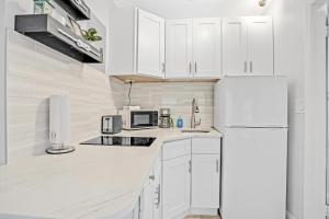 a white kitchen with white cabinets and a refrigerator at Sea Rocket 21 in St. Pete Beach