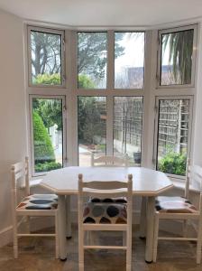 a white table and chairs in a room with windows at Treloyhan Lodge in St Ives