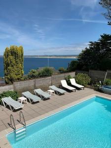 a swimming pool with chaise lounge chairs and a swimming pool at Treloyhan Lodge in St Ives