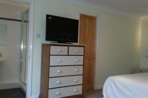 Un dormitorio con un tocador con TV. en Treloyhan Lodge, en St Ives