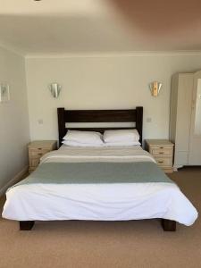 a bedroom with a large bed and two night stands at Treloyhan Lodge in St Ives
