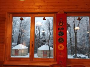 una ventana con vistas a un bosque cubierto de nieve en Kincs Apartman és Jurtaszállás, en Dobogoko