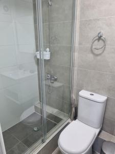 a bathroom with a toilet and a glass shower at Departamento en Tome, Condominio Vista Bahia in Tomé