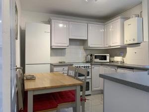 una cucina con armadi bianchi e tavolo in legno di A stunning 3 bedroom house a Londra