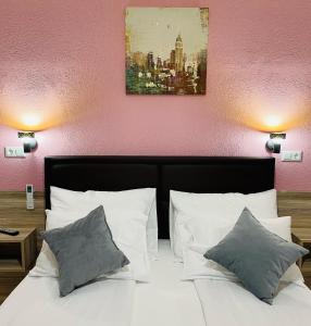 Hotel Casablanca في Goražde: سرير بمخدات بيضاء ولوحة فوقه
